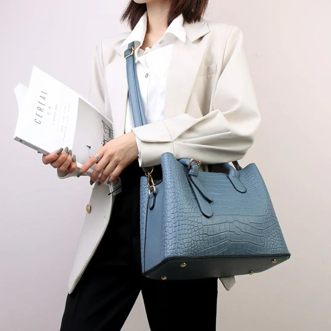 Woman in blazer holding magazine and blue crocodile pattern leather handbag