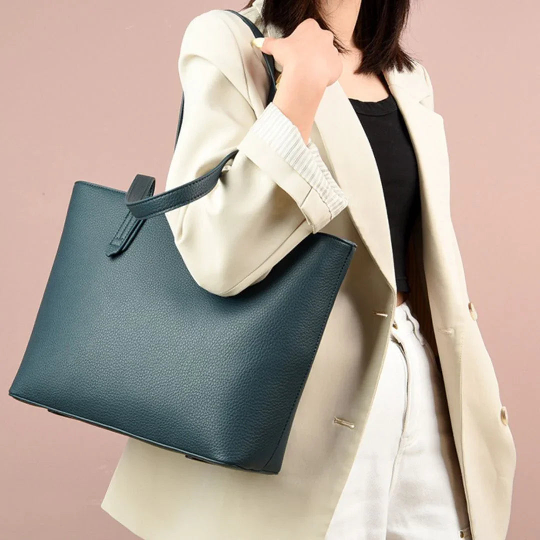 Woman in beige blazer carrying a large dark green leather tote bag