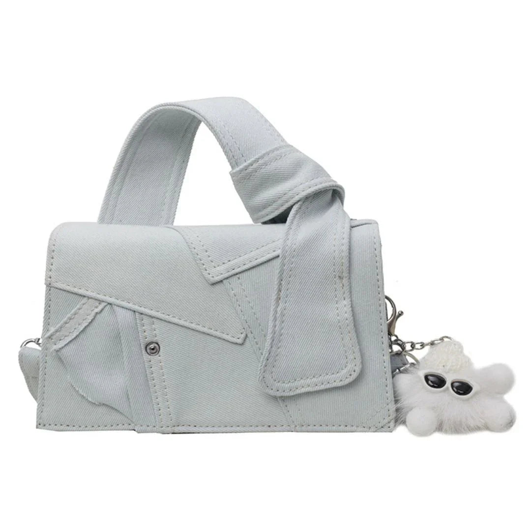 Light blue denim handbag with wide handle and white fuzzy keychain accessory