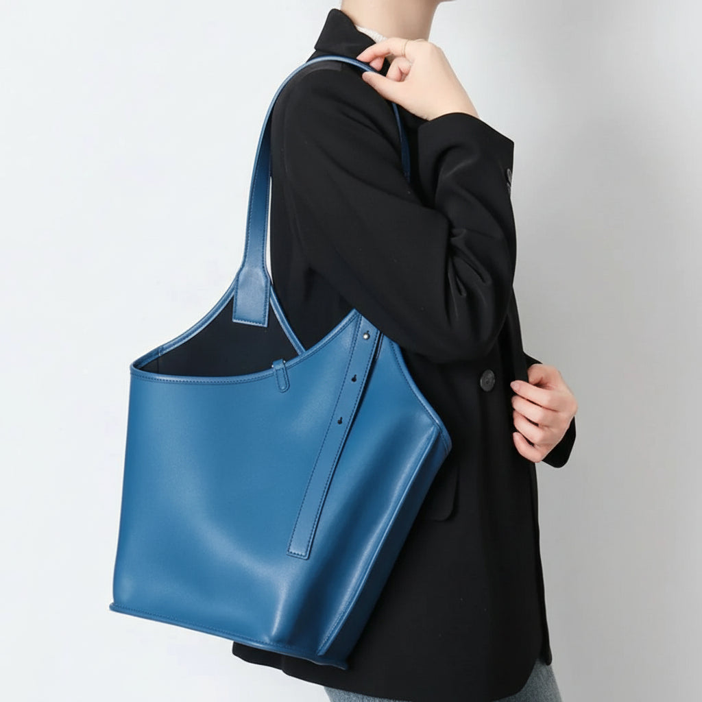 Woman carrying a large blue leather tote bag over shoulder, black blazer outfit