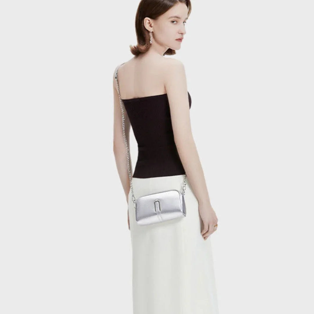 Woman in black tube top and white skirt with metallic silver crossbody bag