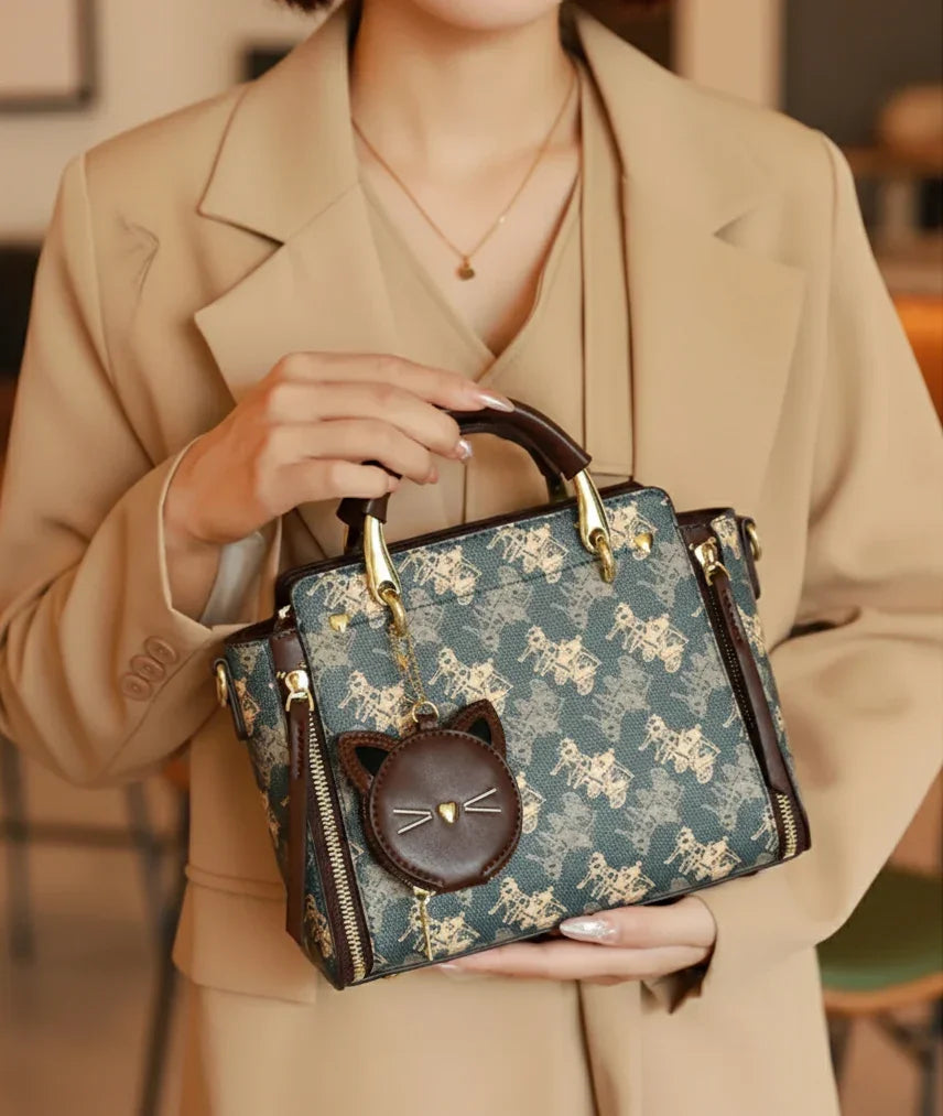 Person holding a patterned handbag with a cat face charm