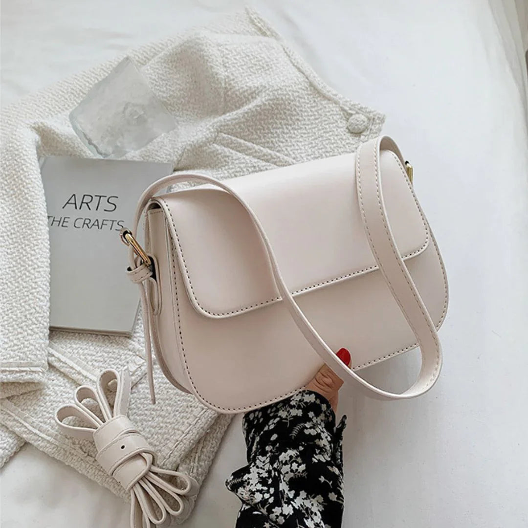Minimalist beige shoulder bag on cream jacket with arts book and floral sleeve