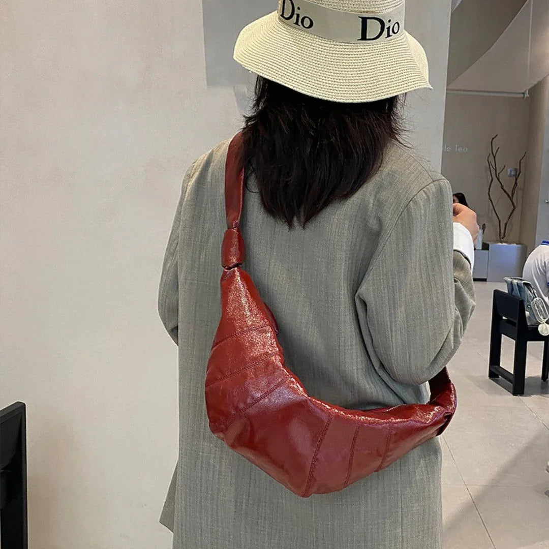 Woman in beige hat and blazer with shiny red shoulder bag in modern cafe
