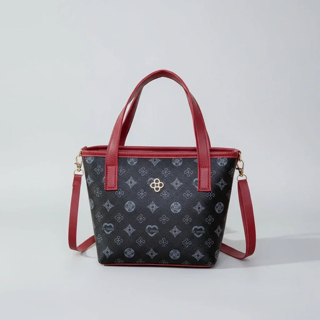 Black handbag with red handles, floral pattern, gold logo, and detachable shoulder strap