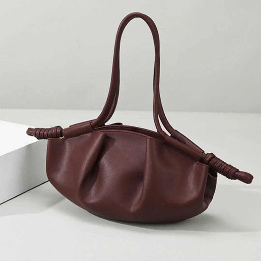 Burgundy leather ruched handbag with knotted handles on a white table