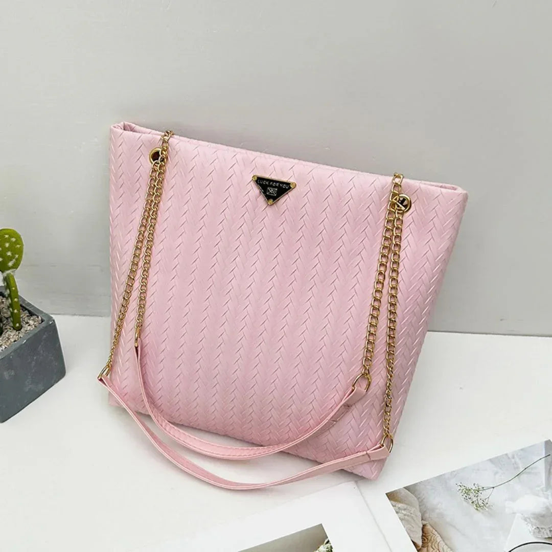 Pink textured tote handbag with gold chain straps on white background