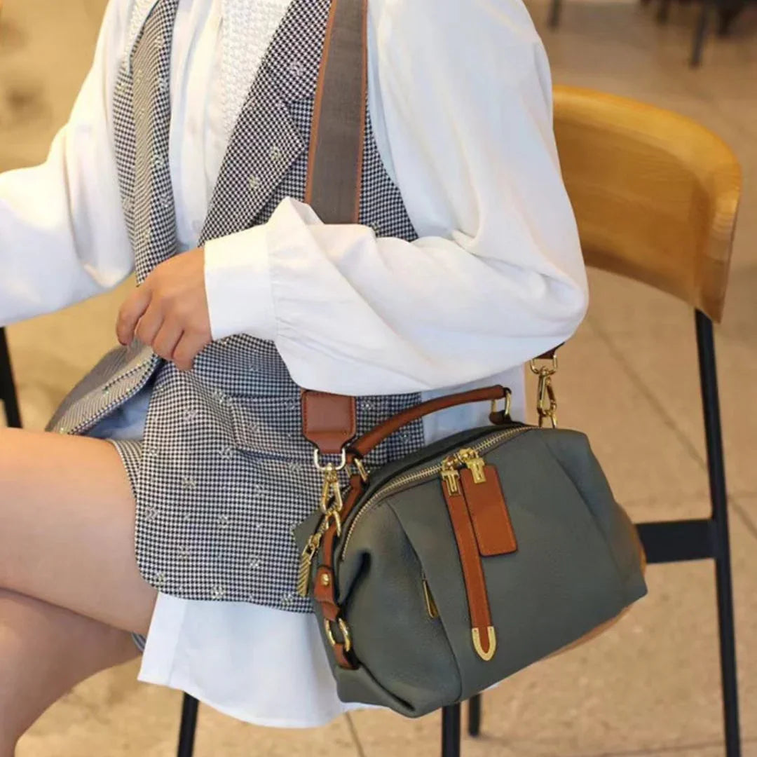 Woman in a checkered vest and white blouse sitting with a stylish gray leather handbag