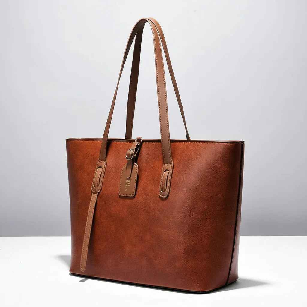 Brown leather tote bag with dual handles and tag on white background