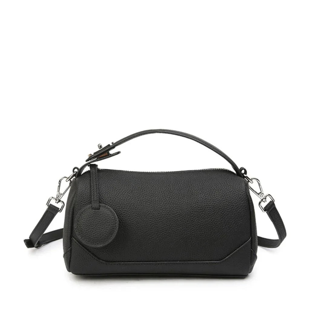 Black leather barrel handbag with top handle, shoulder strap, and round coin pouch.