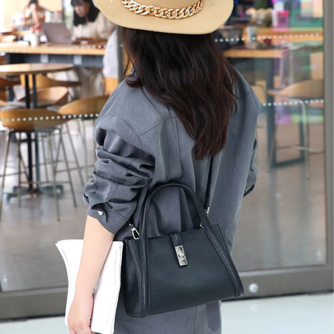 Woman in gray blazer with beige hat and black leather handbag at a modern café