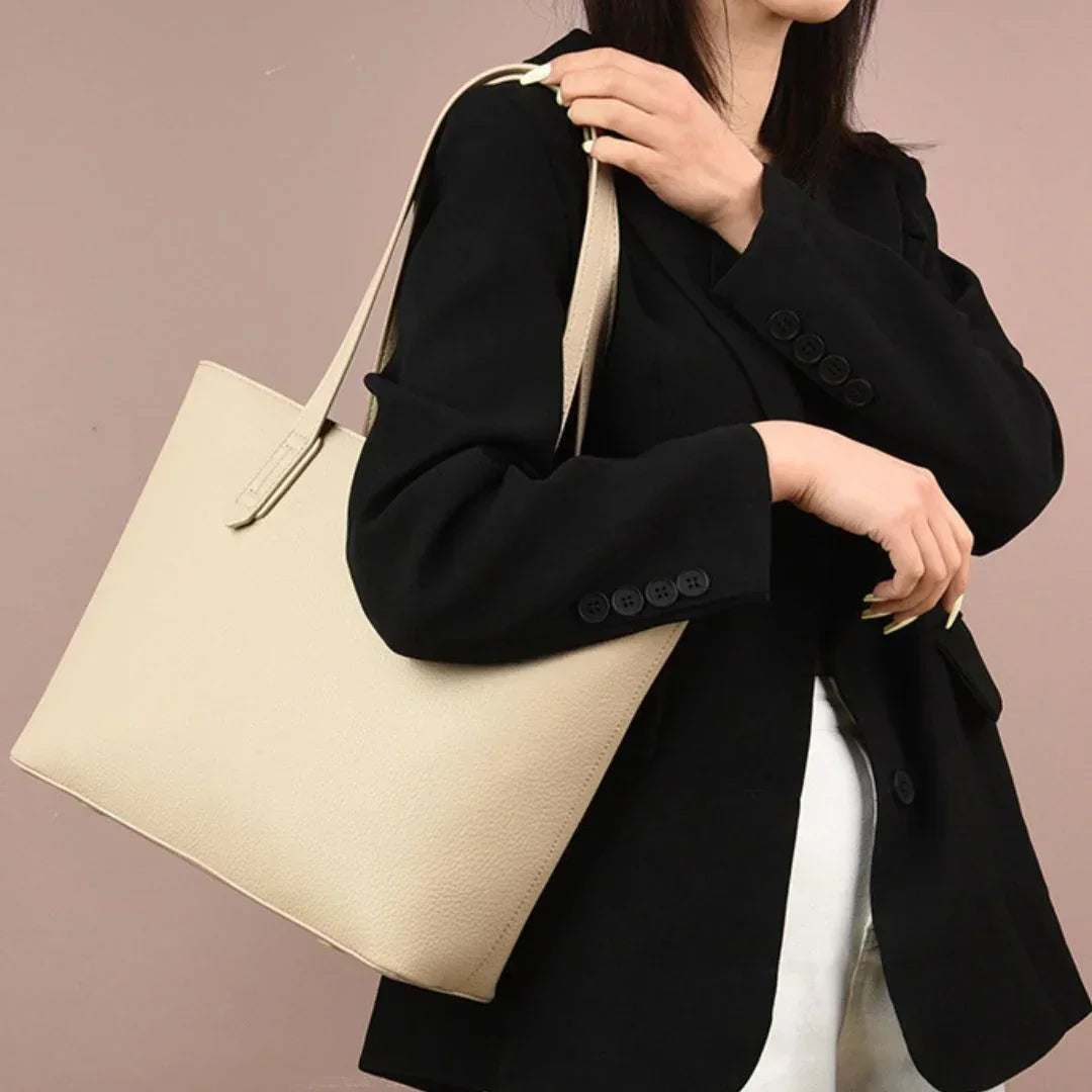 Woman in black blazer carrying a beige leather tote bag, stylish fashion accessory