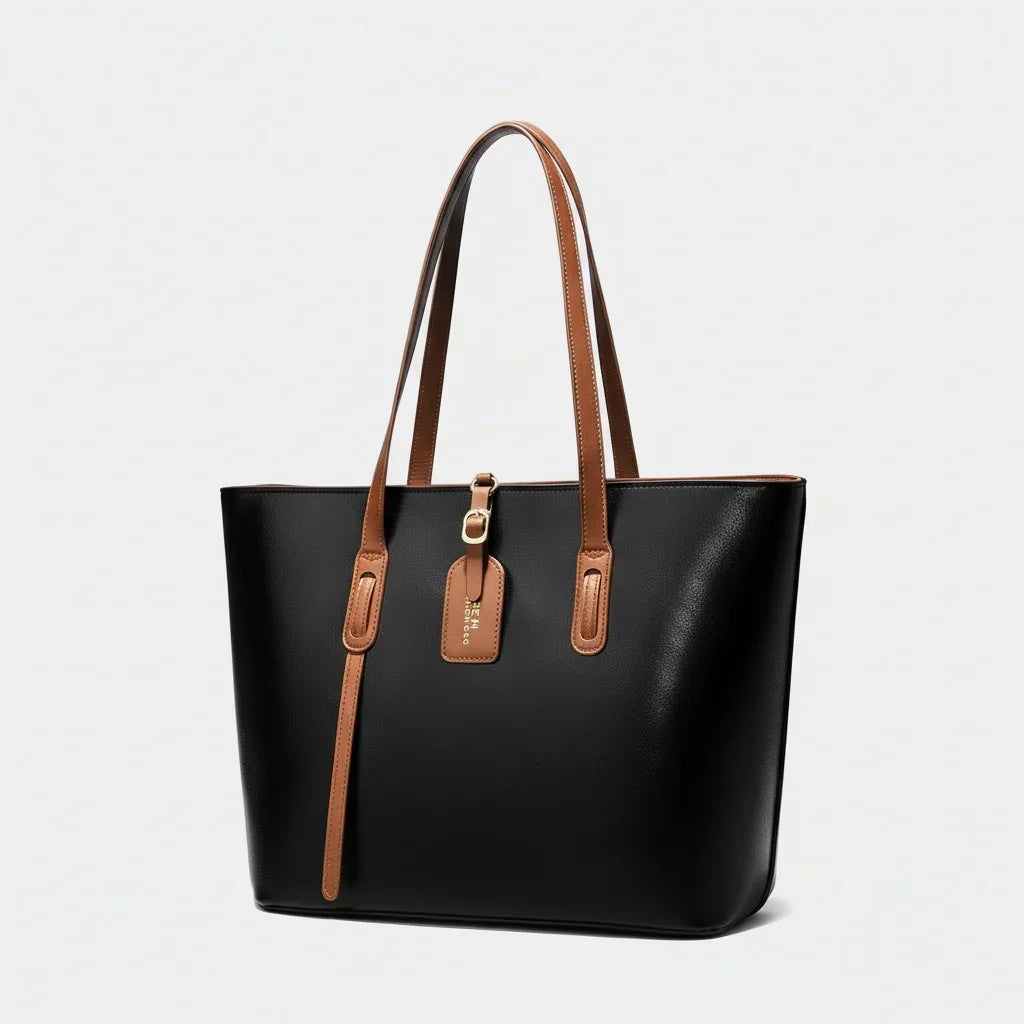 Black leather tote bag with brown handles and gold hardware on white background