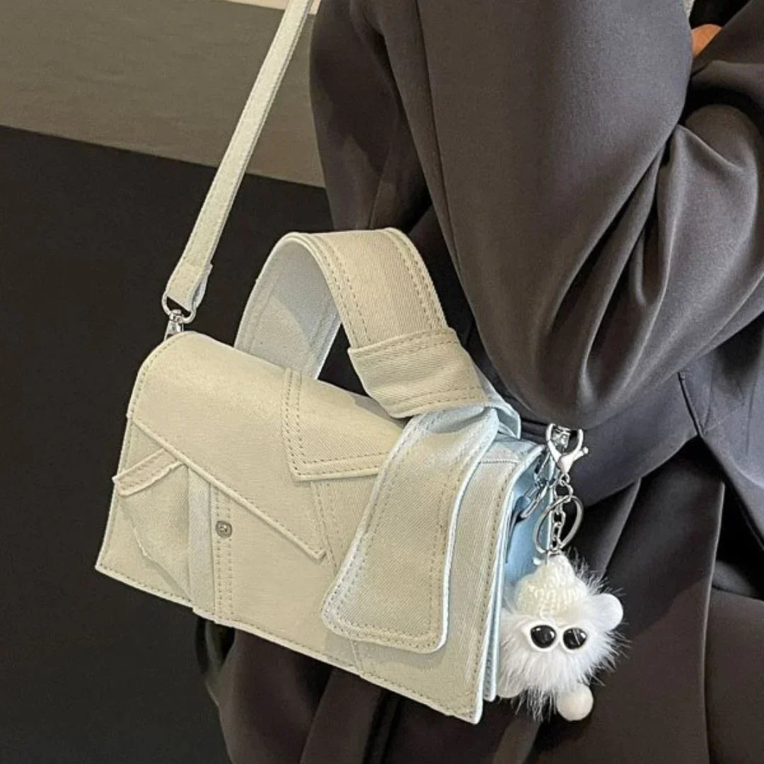 White crossbody bag with shirt pocket design and fluffy keychain, worn over black coat