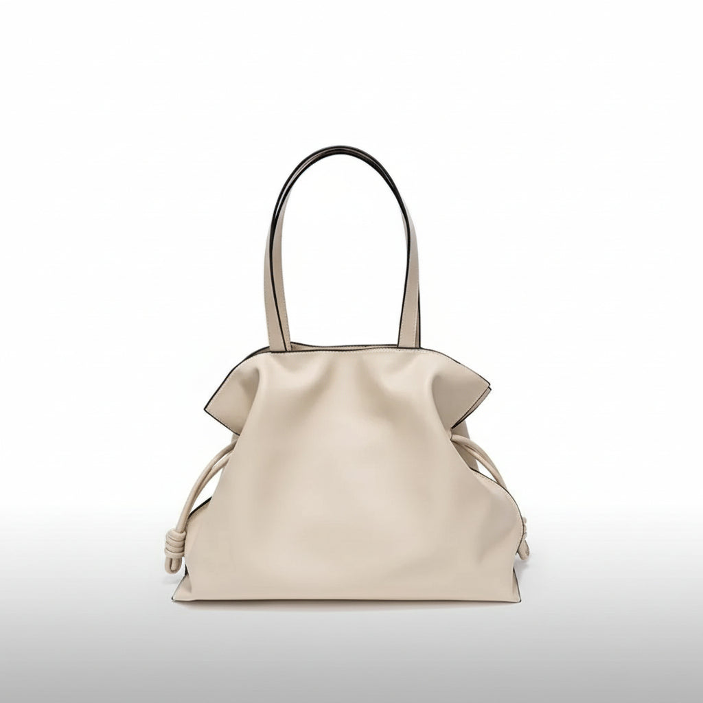 Beige leather tote bag with double handles and knotted side details on white background