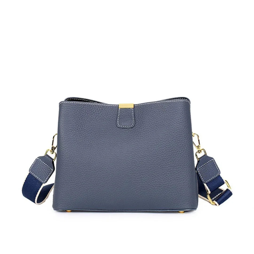 Navy blue leather crossbody bag with gold hardware and adjustable strap on white background