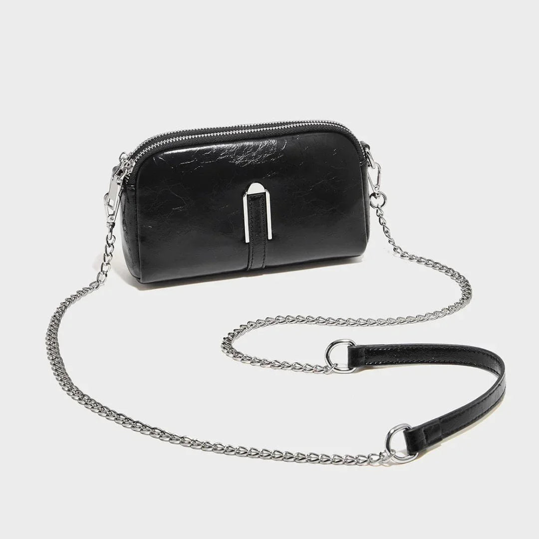 Black leather crossbody bag with silver chain strap on white background