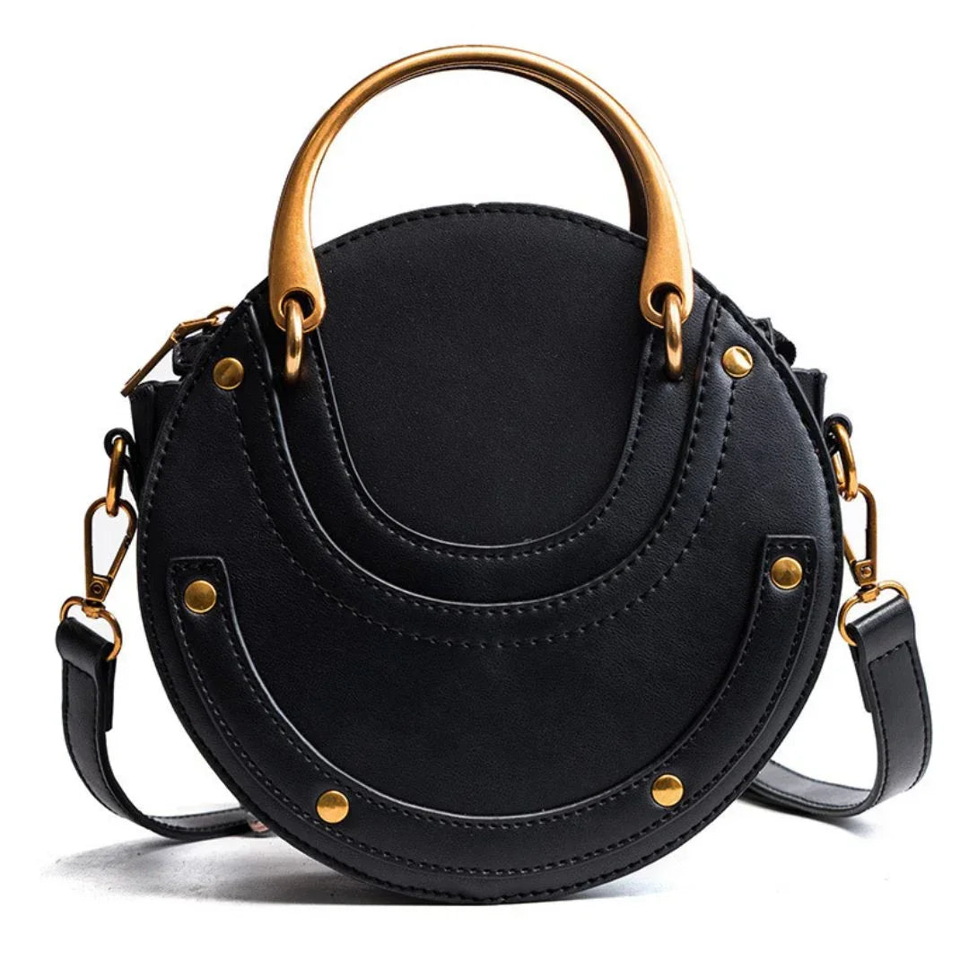 Round black leather handbag with gold hardware and top handle on white background