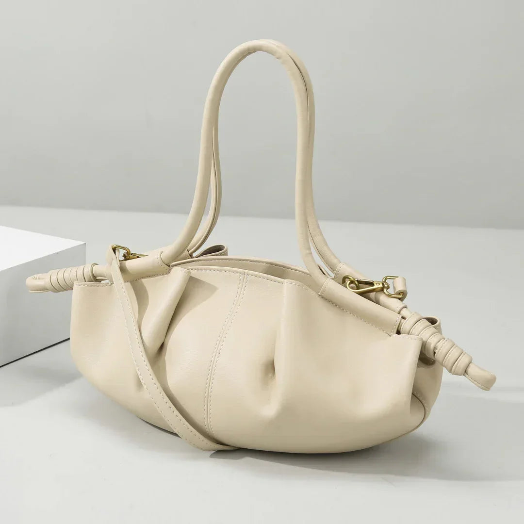 Beige leather handbag with ruched details and double handles on a white background