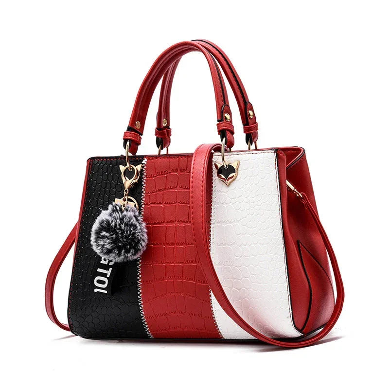 Red, black, and white crocodile pattern handbag with gold heart hardware and fur pom pom keychain