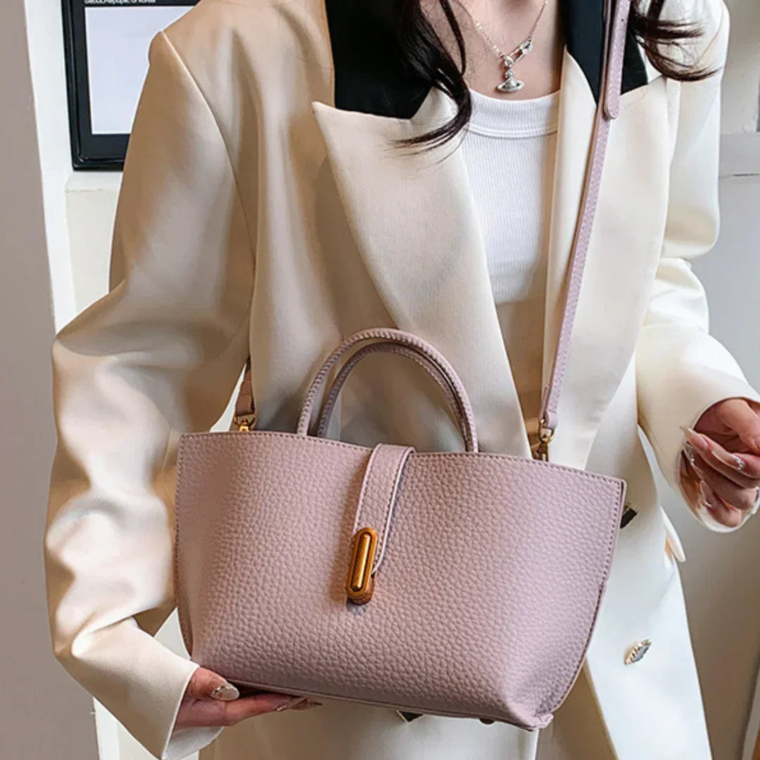 Woman in cream blazer with black lapels holding a textured pink leather handbag