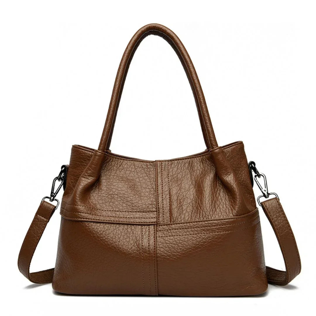 Brown leather handbag with double handles and a detachable shoulder strap on white background