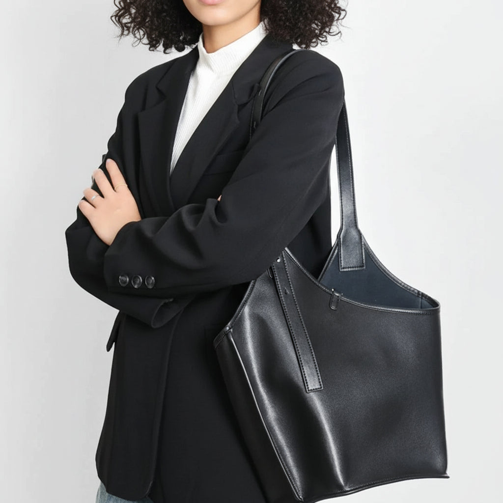 Woman in black blazer carrying a large black leather tote bag on her shoulder