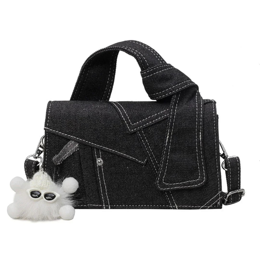 Black denim handbag with white stitching and a fluffy white sunglasses keychain
