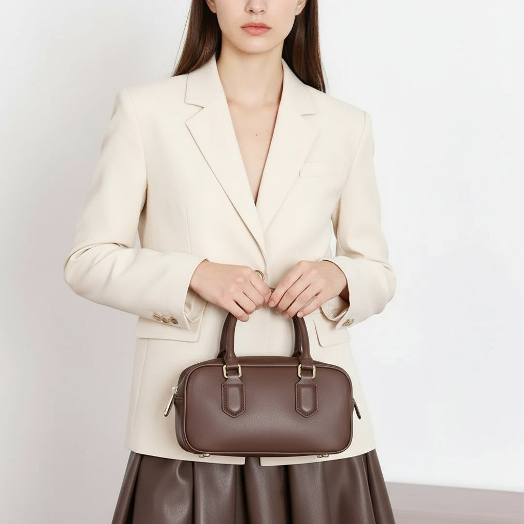 Woman in cream blazer holding brown leather handbag, fashion accessory product photo