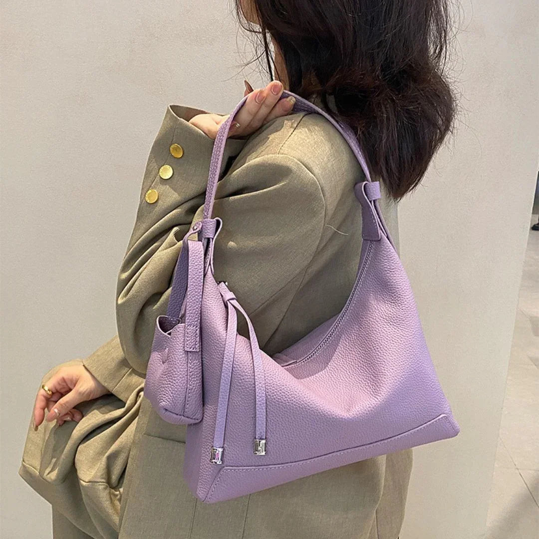 Woman in beige blazer carrying a lavender shoulder bag with gold button details