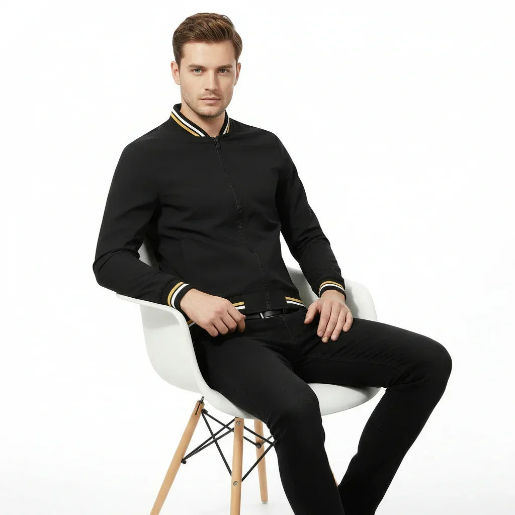 Man wearing a black bomber jacket with yellow accents on a white background