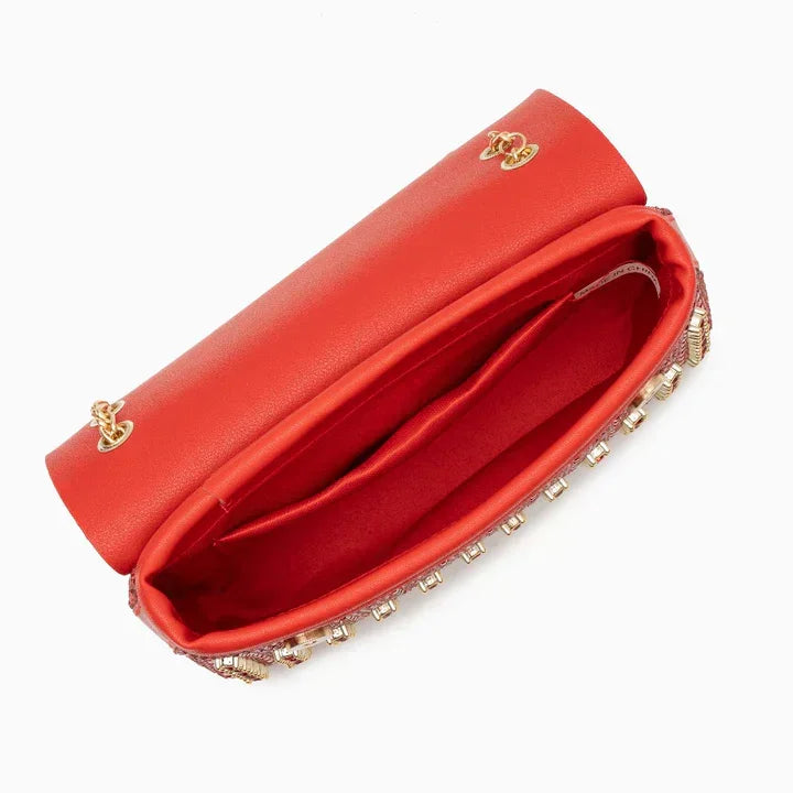 Open red clutch purse with gold chain strap and studded crystal trim on white background