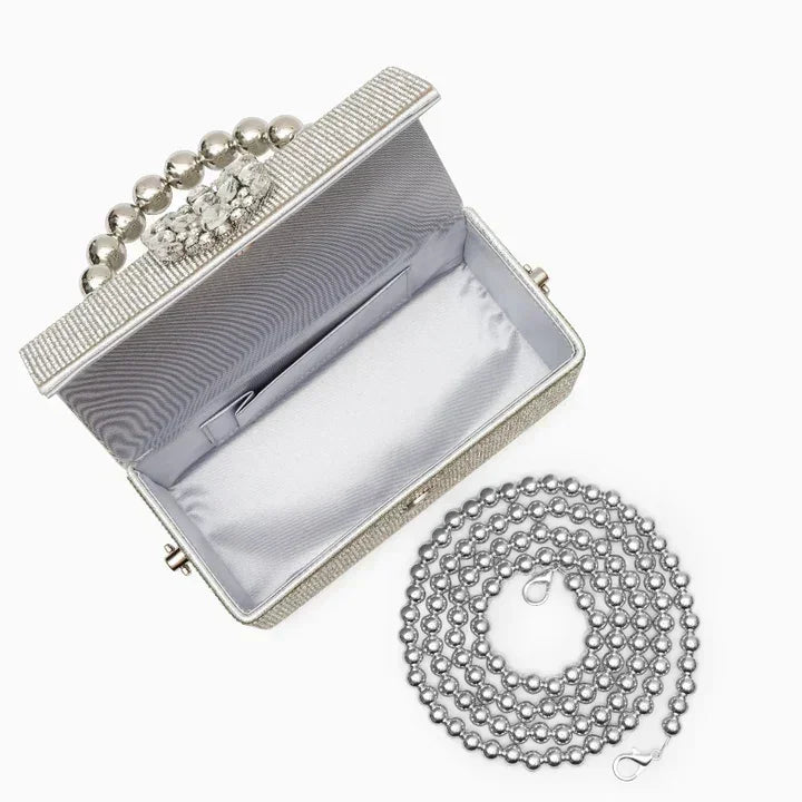 Silver beaded evening clutch bag with pearl handle and detachable chain strap on white background