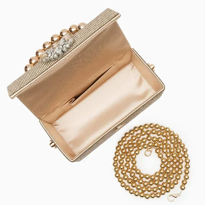 Gold beaded evening clutch with crystal clasp and matching gold chain strap on white background.
