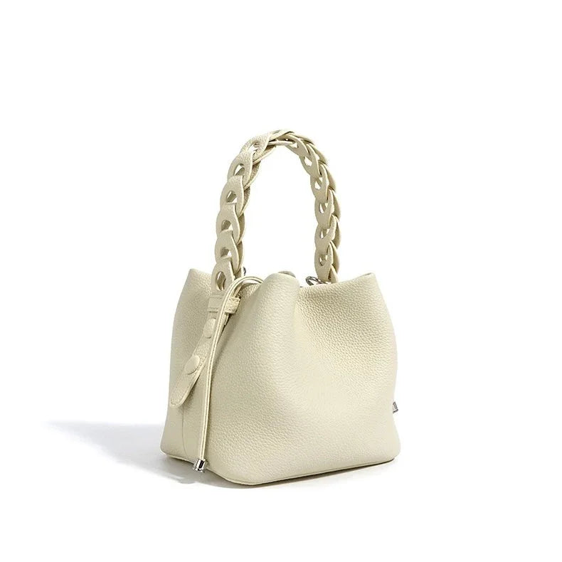 Ivory leather bucket bag with textured finish and chunky braided handle on white background