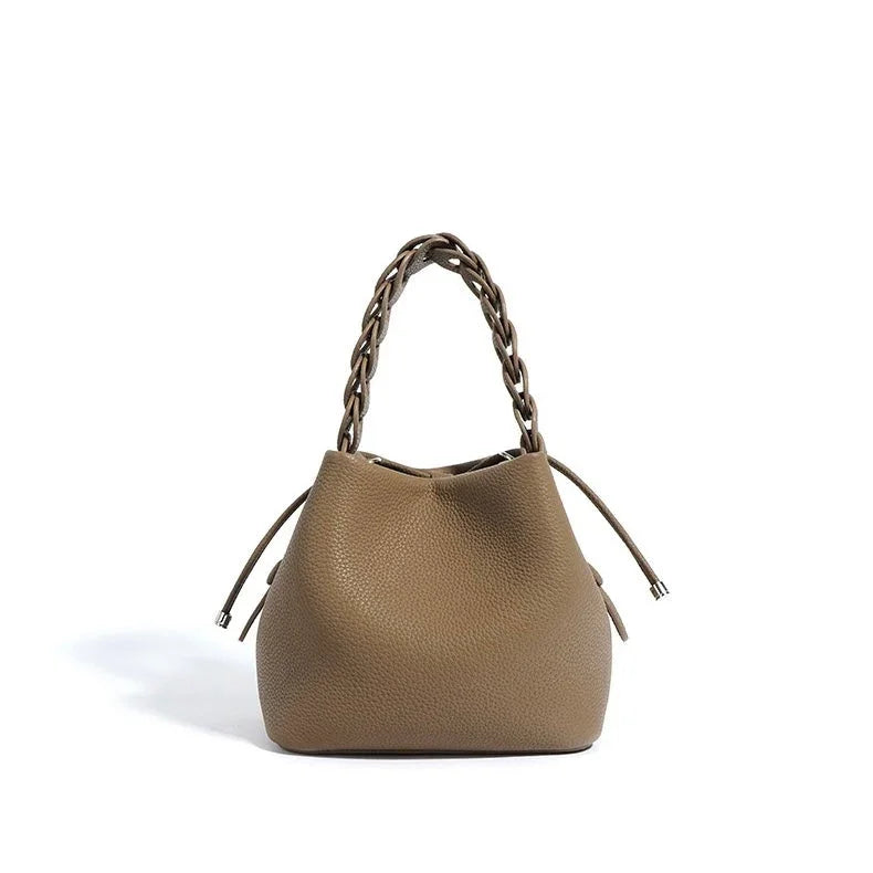 Taupe leather tote bag with braided handle and drawstring closure on white background
