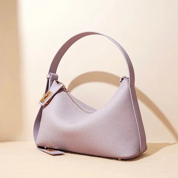 Lavender leather shoulder bag with gold zipper on beige background