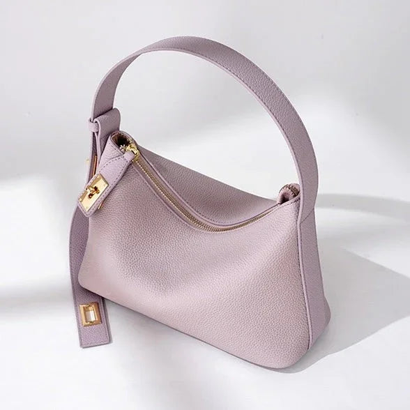 Light purple leather handbag with gold zipper and buckle on a white background