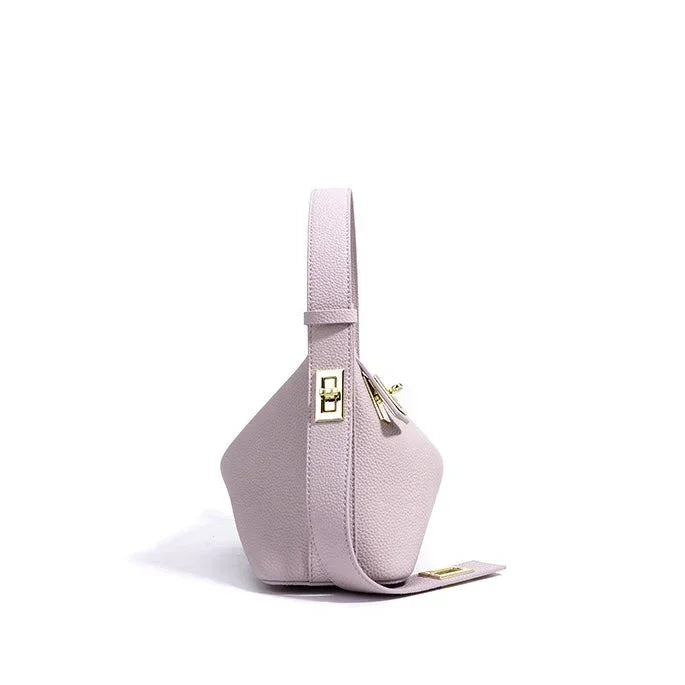 Light pink leather handbag with gold hardware, modern geometric design, white background