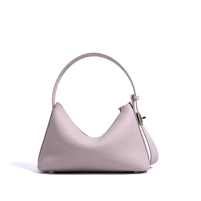 Pastel purple leather handbag with top handle and gold hardware on white background