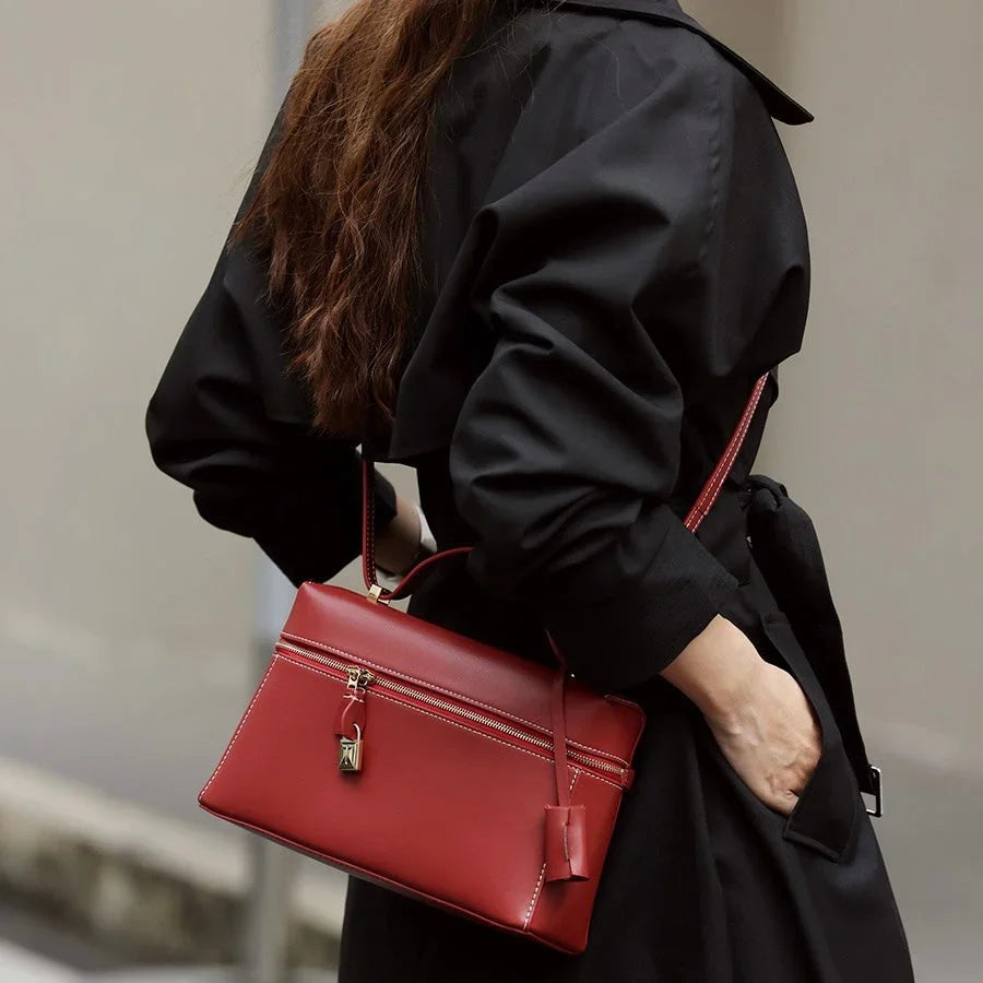 Woman in black coat carrying a stylish red leather handbag with gold hardware