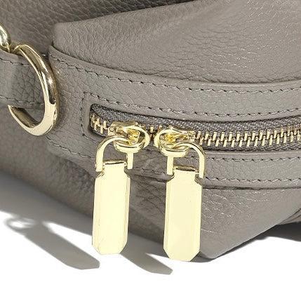 Close-up of a gray leather handbag with gold zipper and double gold zipper pulls
