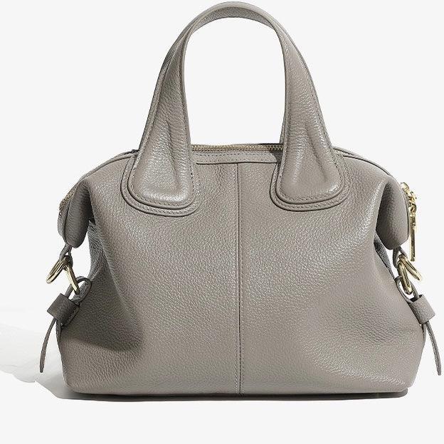 Taupe leather handbag with gold hardware and double handles on a white background