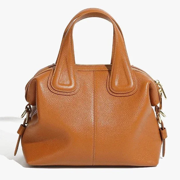 Brown leather handbag with gold hardware and short handles on white background