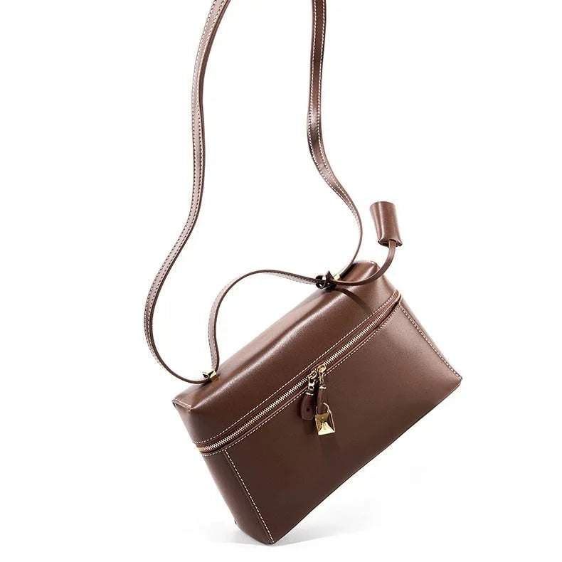 Brown leather crossbody bag with zipper, gold lock, and adjustable strap on white background