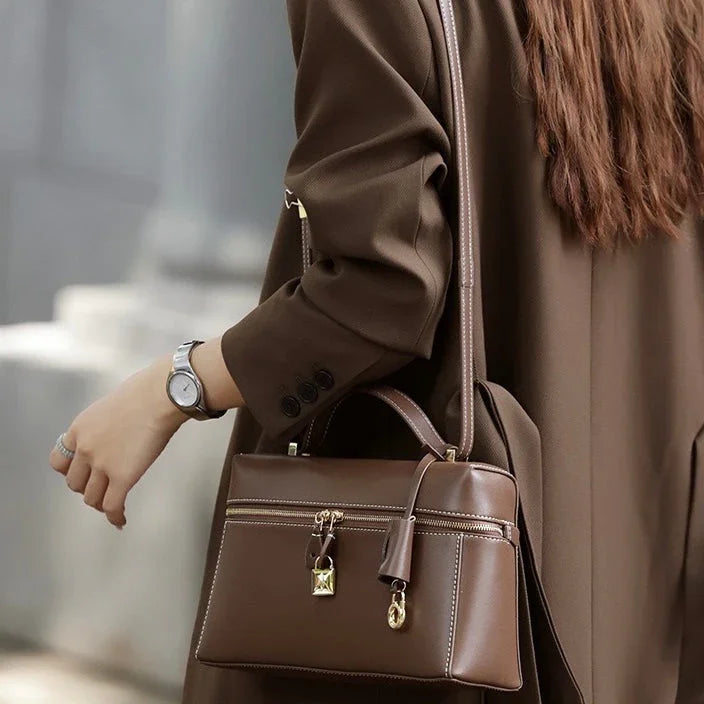 Woman in brown coat with brown leather handbag and silver watch outdoors