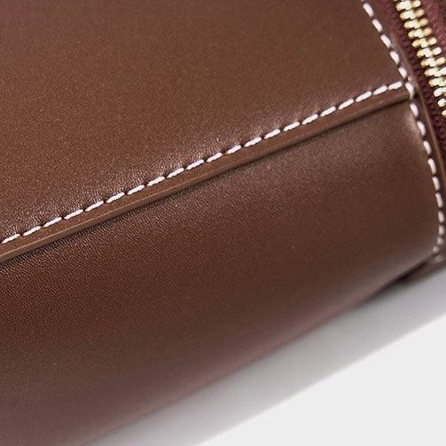 Brown leather bag with white stitching and gold zipper close-up