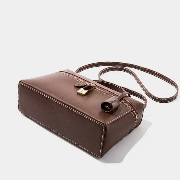 Brown leather crossbody bag with white stitching, gold zipper, and padlock detail