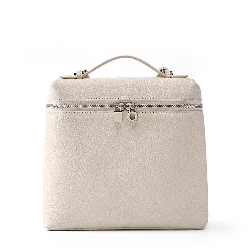 Beige leather handbag with top handle and silver zipper on white background
