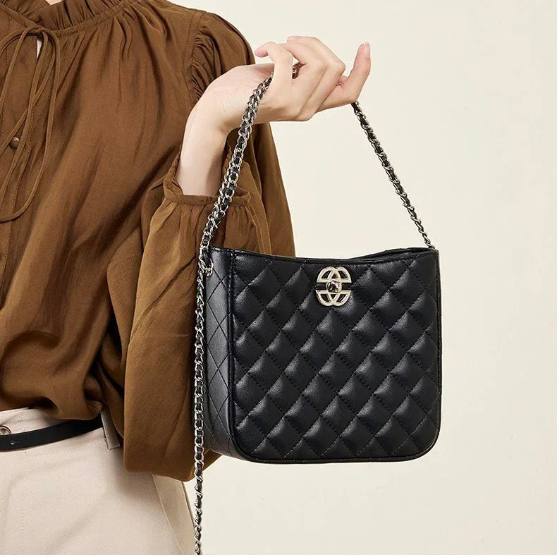 Woman holding black quilted leather shoulder bag with chain strap and gold logo